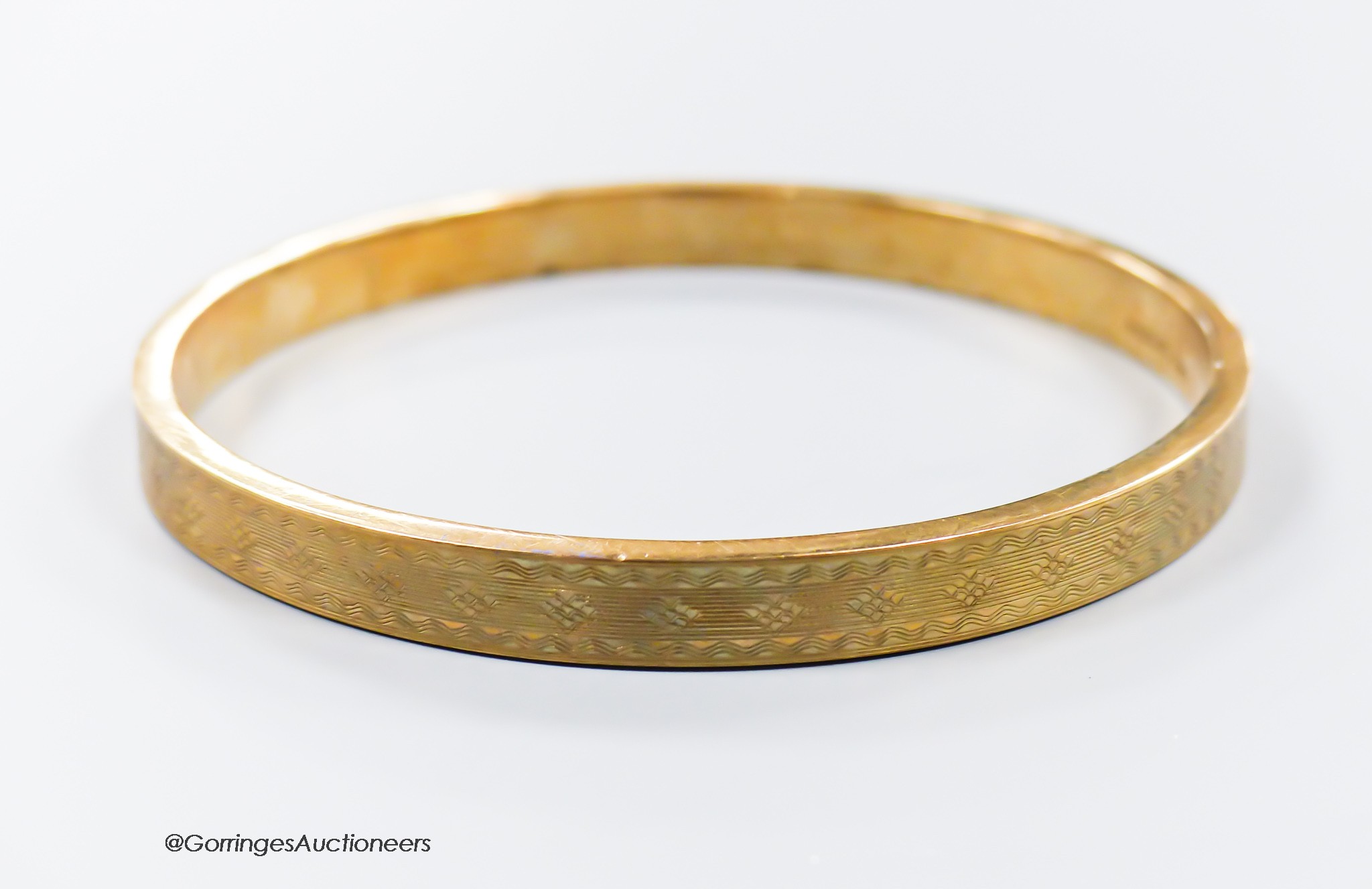 A 1920's engine turned 9ct gold bangle, interior diameter 76mm, 11.9 grams.